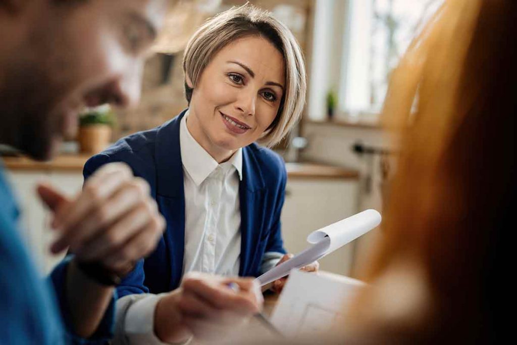 Smiling Mortgage Loan Officer going through paperwork communicating with her clients meeting